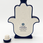A Casa de Hamsa Blanco Tequila Candle in a Hamsa hand-shaped, patterned bottle sits beside its matching cap on a white background—ideal for display or as a standout decor piece.
