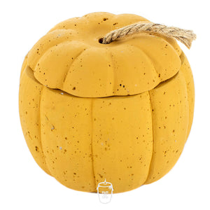 The Yellow Cement Pumpkin Candle features a small, round, pumpkin-shaped cement container with a textured surface and a rope stem on the lid.