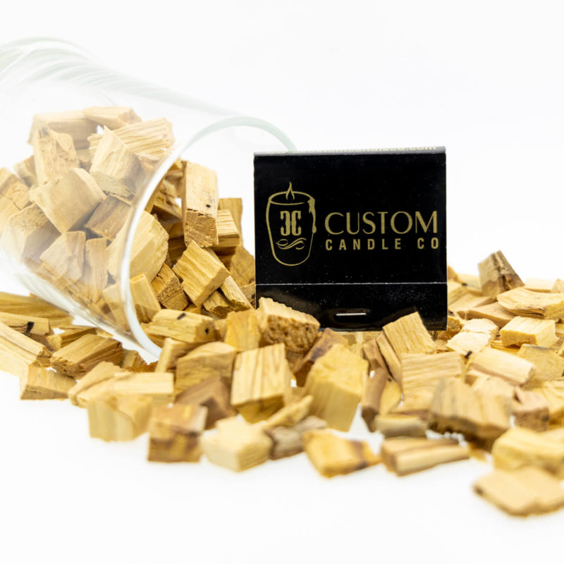 Palo Santo wood Chips spilled on a surface with the a book of Custom Candle branded matches