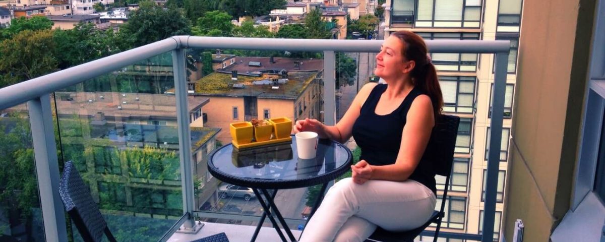 Woman enjoying morning coffee on a balcony of a high rise overlooking the city outdoor