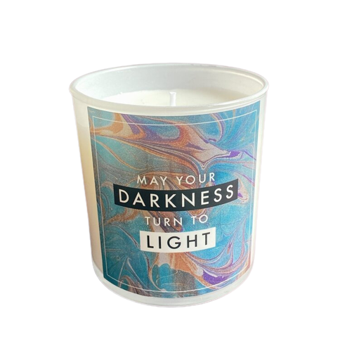 A white container with white wax with the quote "May your darkness turn into light."