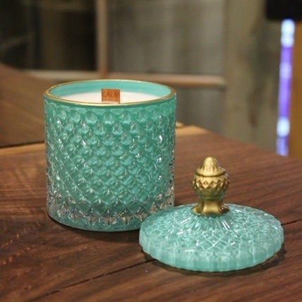 An Elegant Turquoise Crystal scented candle on a wooden table.