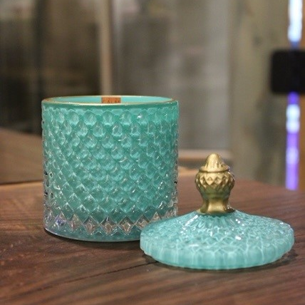 An elegant Turquoise Crystal Scented Candle on a wooden table.