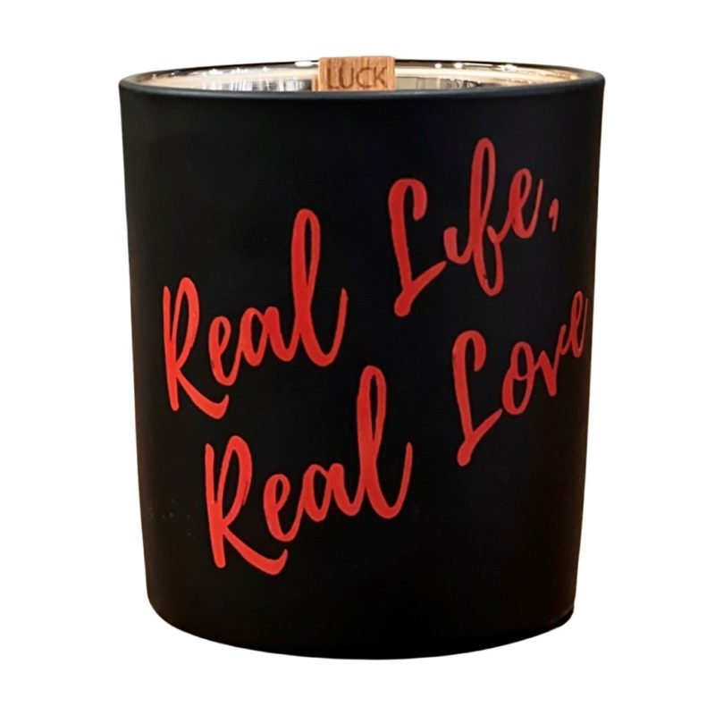 Real life, Real Love scented candle with a wick that says "Luck" in a black container