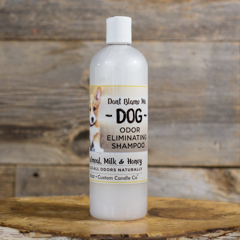 A bottle of Dog Shampoo - Oatmeal Milk Honey 16oz sitting on a wooden table.