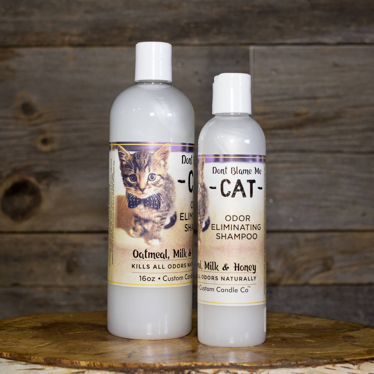 Two bottles of Cat Shampoo - Oatmeal Milk Honey 8oz and 16oz on a wooden table.