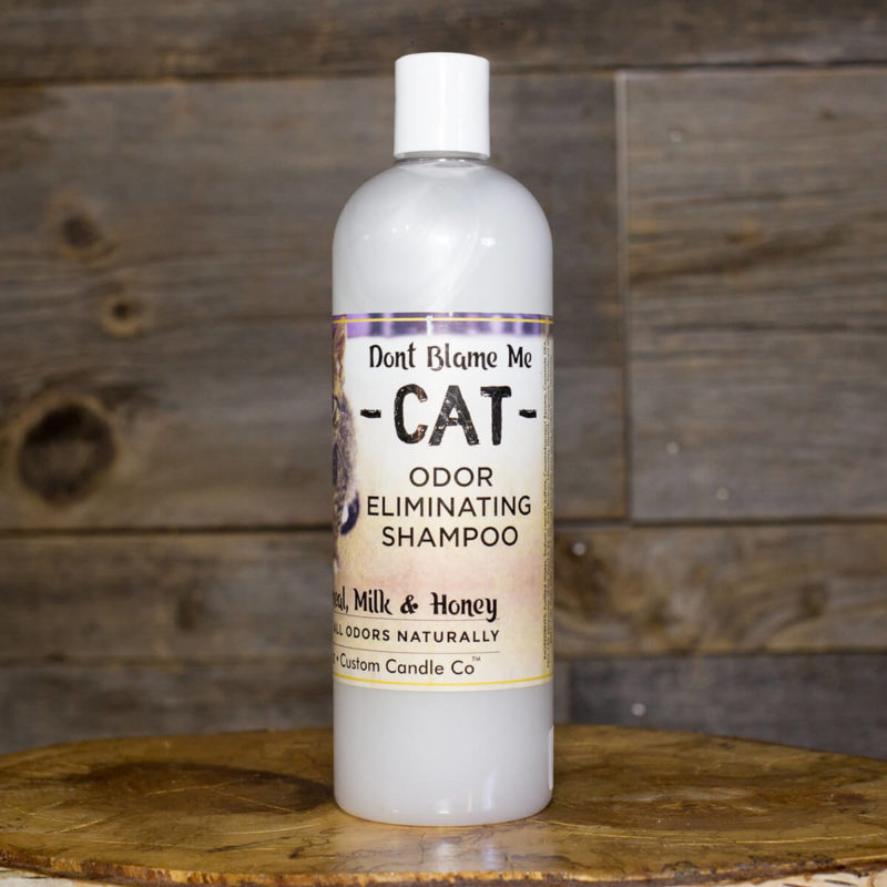 A bottle of Cat Shampoo - Oatmeal Milk Honey 16oz sitting on a wooden table.
