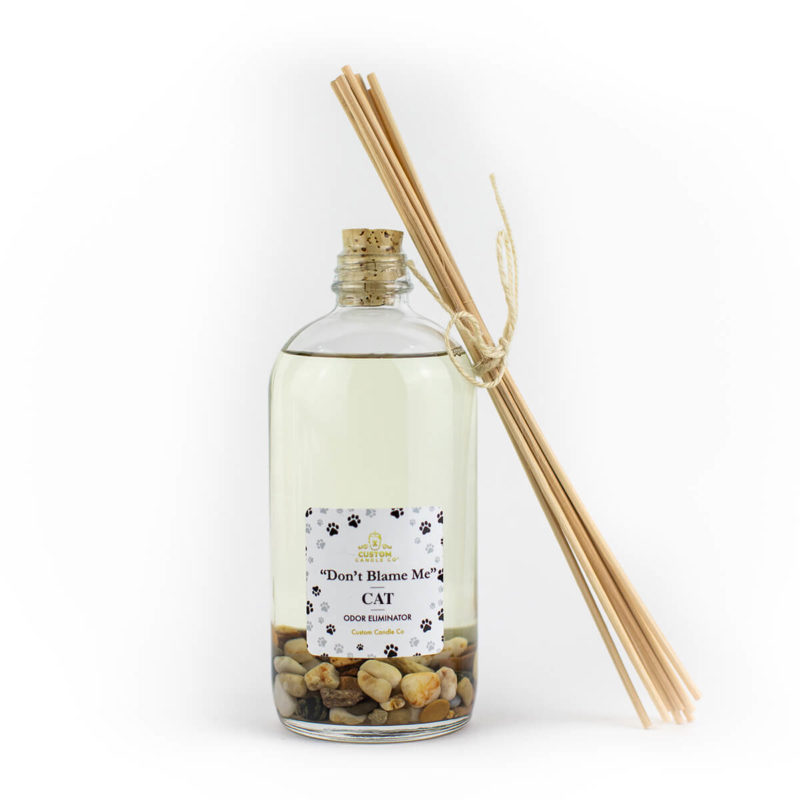 A bottle of "Don't Blame Me" Cat Diffuser Odor Eliminator with a collection of wooden sticks.