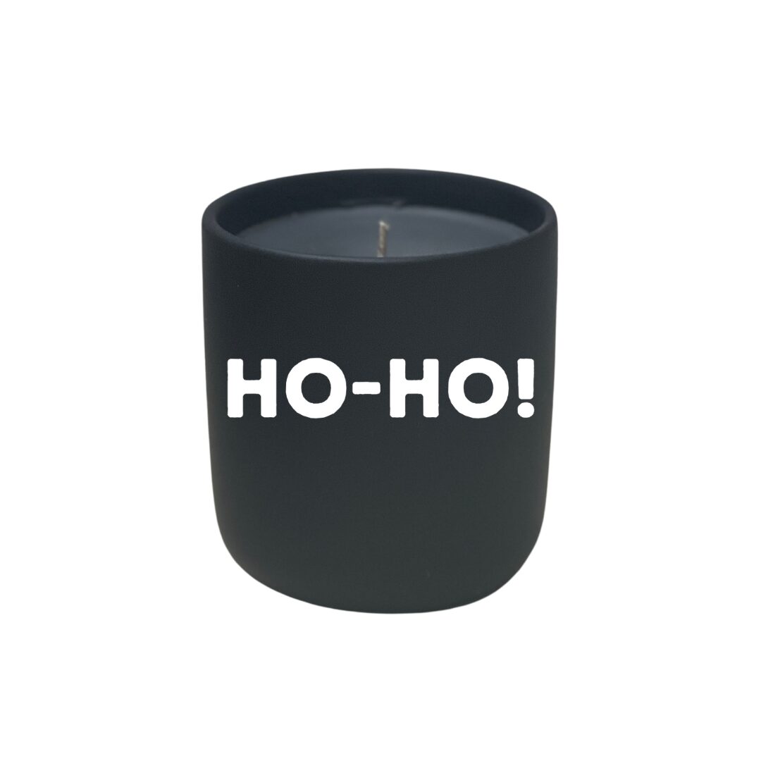 A Quoted Candle - Ho-Ho, with the word ho ho written on it, nestled in a black jar.